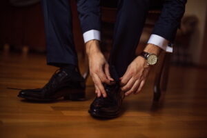 Photo of sharp dressed man in black tying black dress shoes
